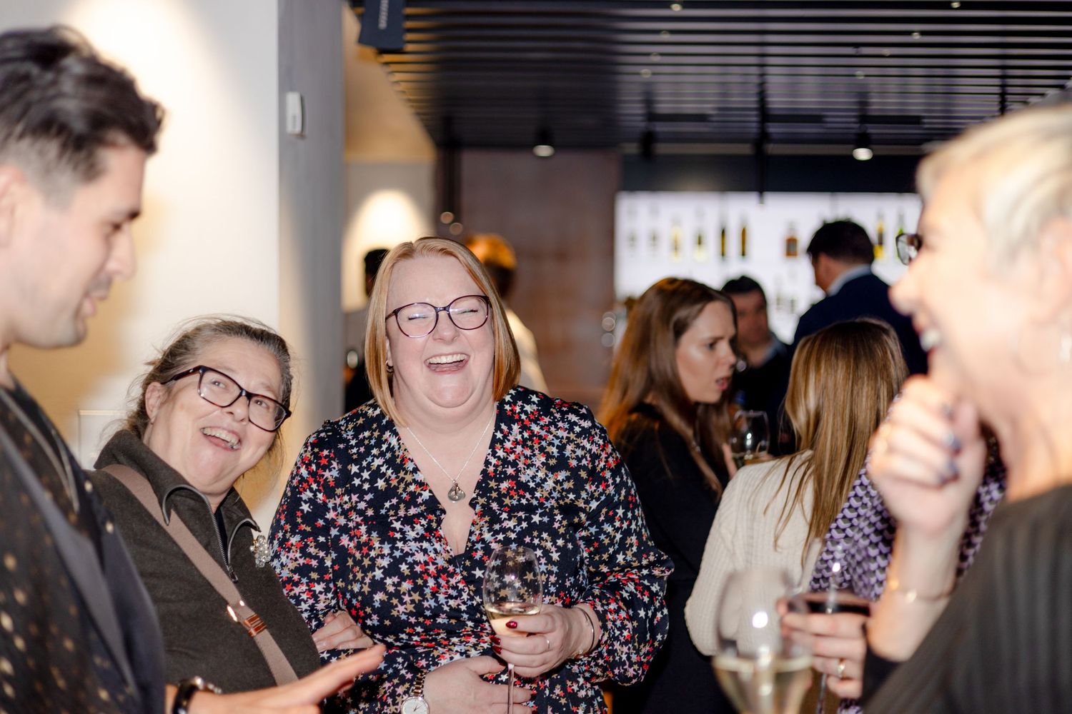 A group of people laughing and socializing at an indoor networking event.