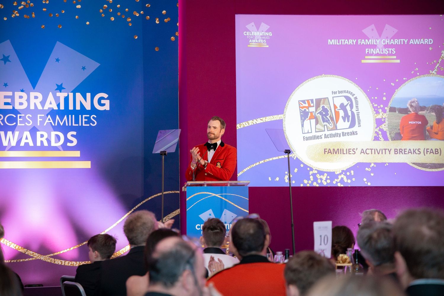 Corporate event space with blue and purple lighting showing celebration graphics on multiple displays.