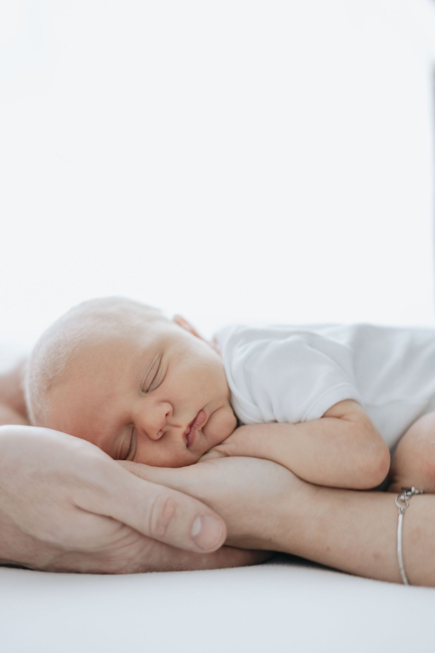 Peaceful sleeping newborn photos in soft white tones showing delicate details.