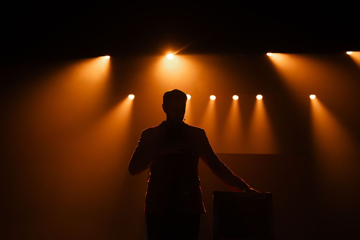 Dramatic silhouettes against warm orange stage lighting creating an atmospheric scene.
