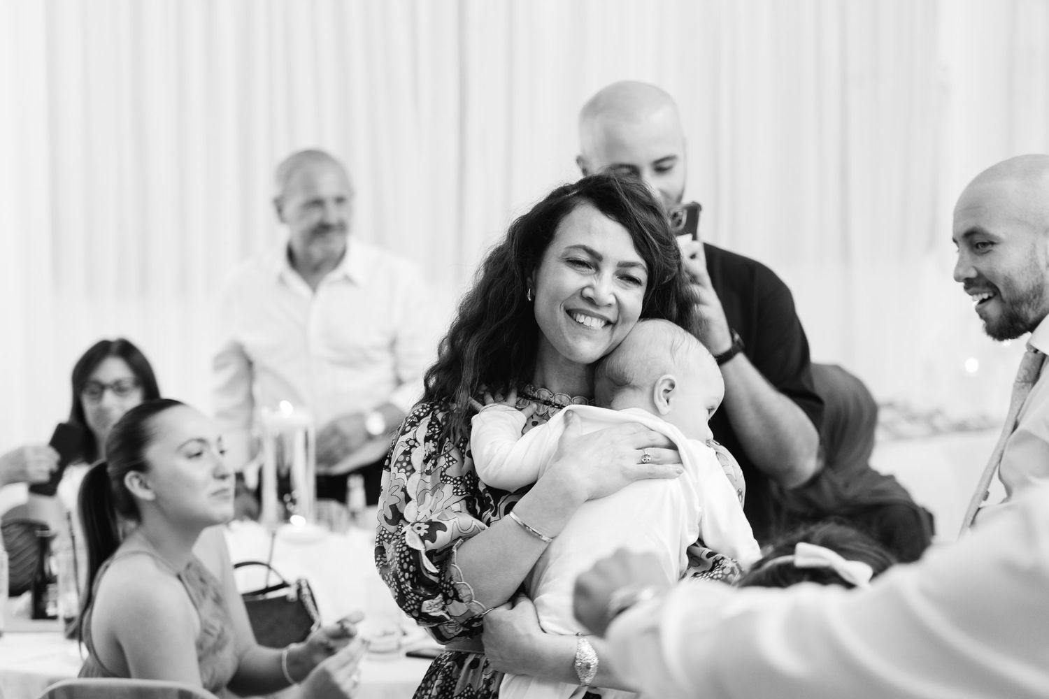 Wedding reception guests celebrate with laughter and dancing in a bright venue.
