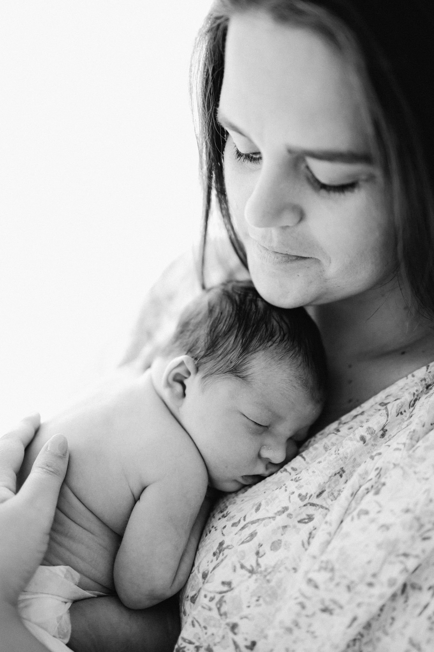 Tender black and white newborn photos showing peaceful sleeping against floral fabric.