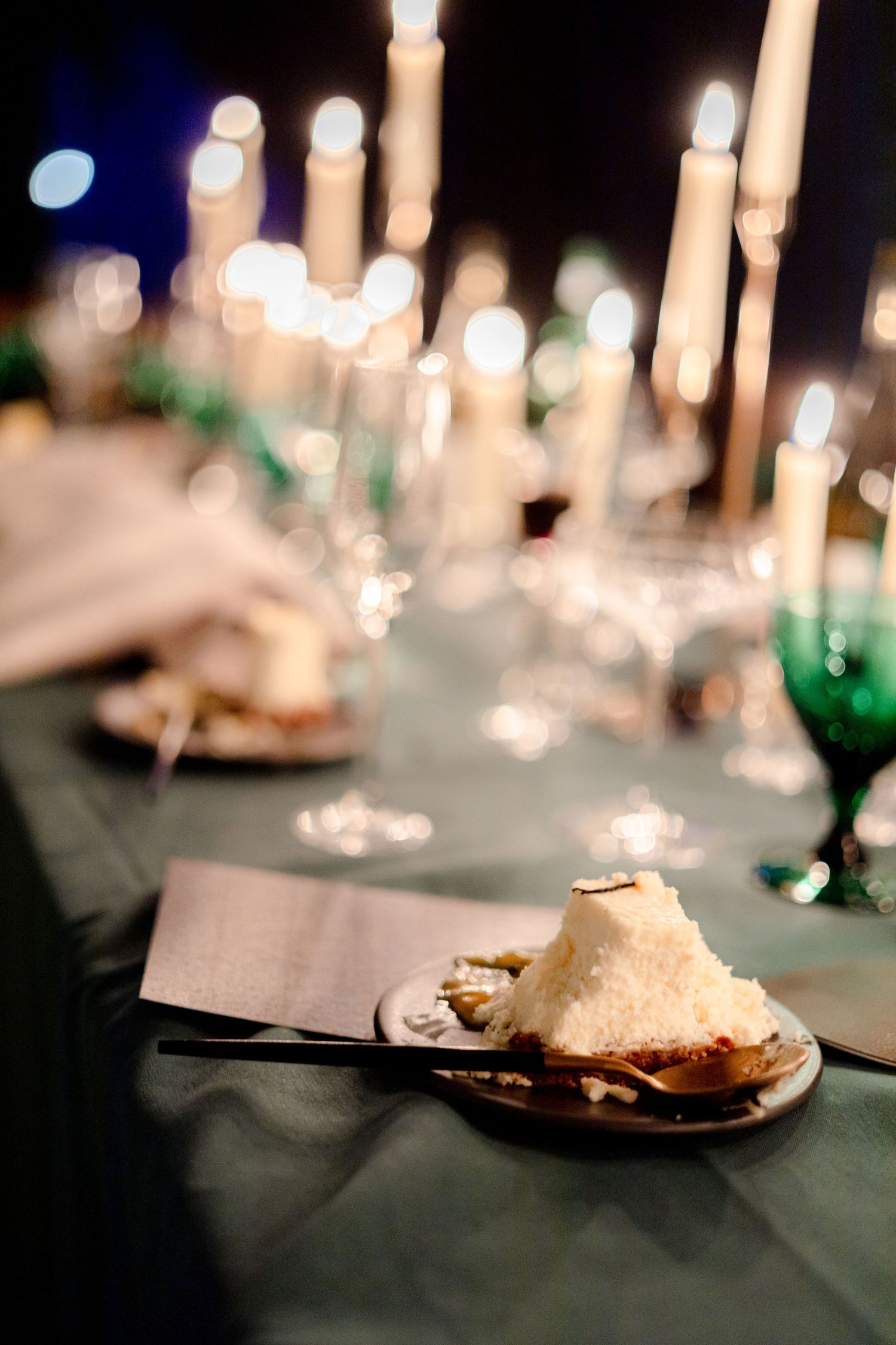 Candlelit table settings with dessert plates at an elegant dinner party.