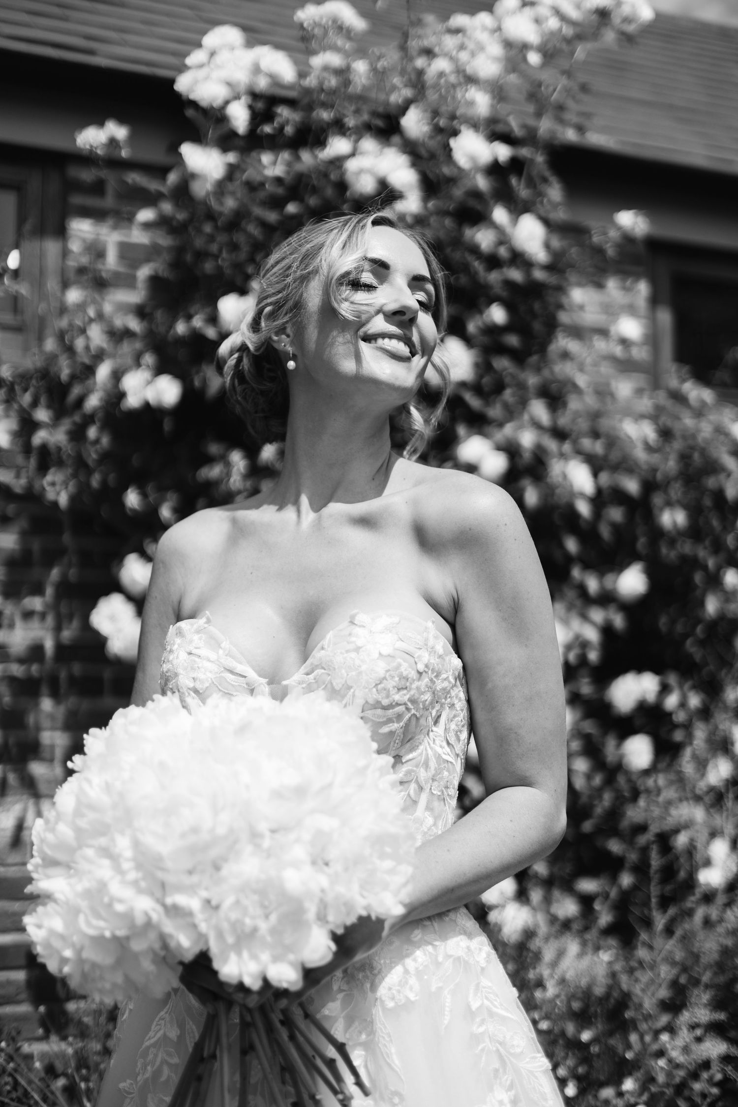 Black and white bridal portraits in a garden with white roses.