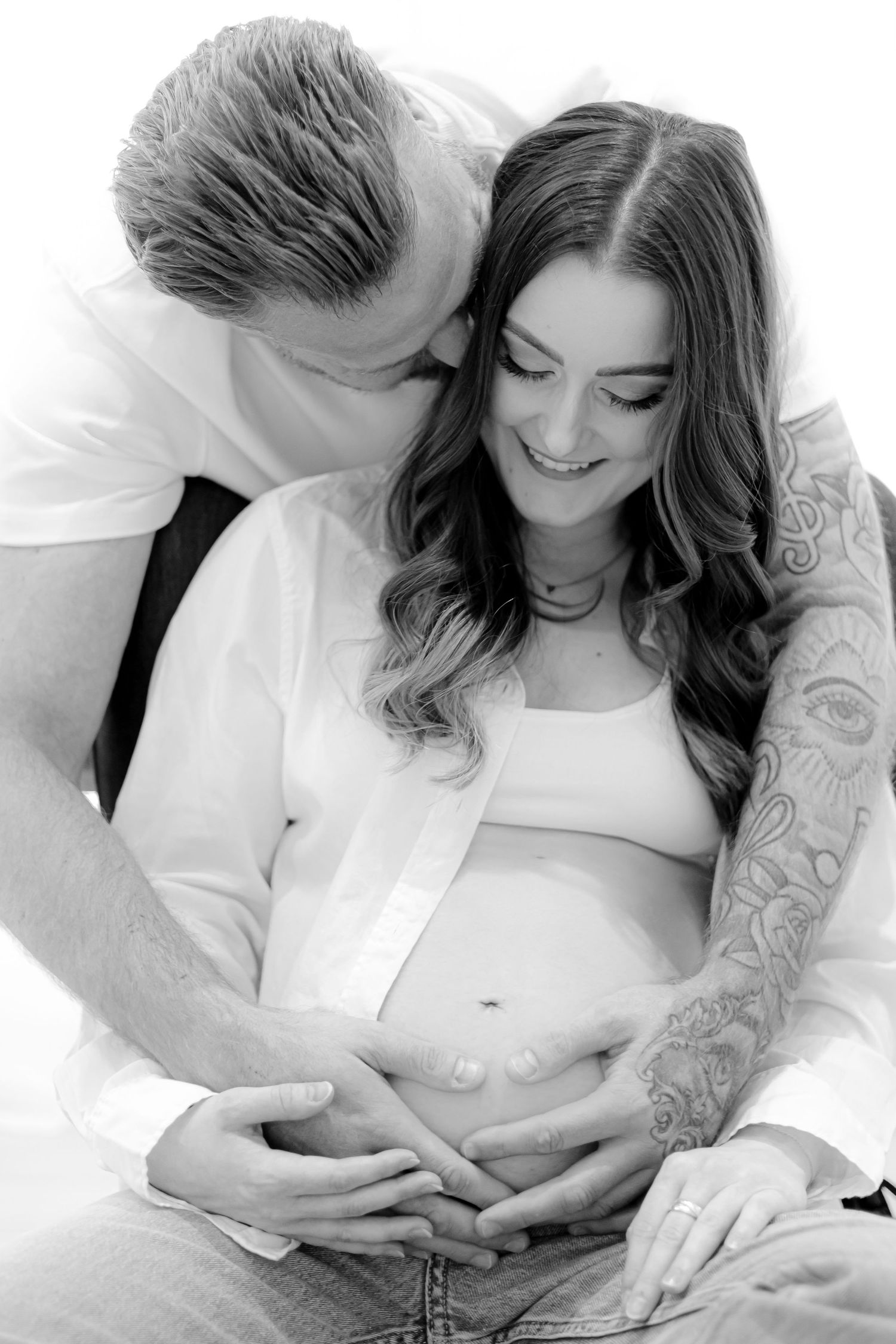 Intimate black and white maternity photo of couple sharing tender moment.