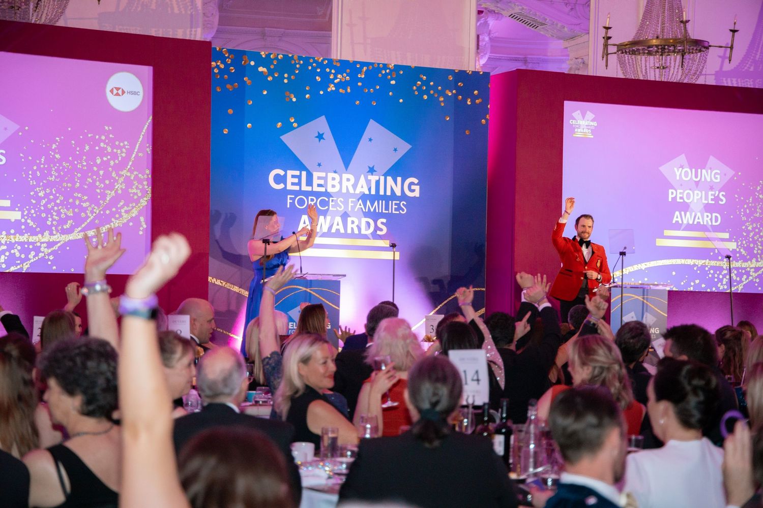 Crowd of attendees at an awards celebration with purple and blue ambient lighting.
