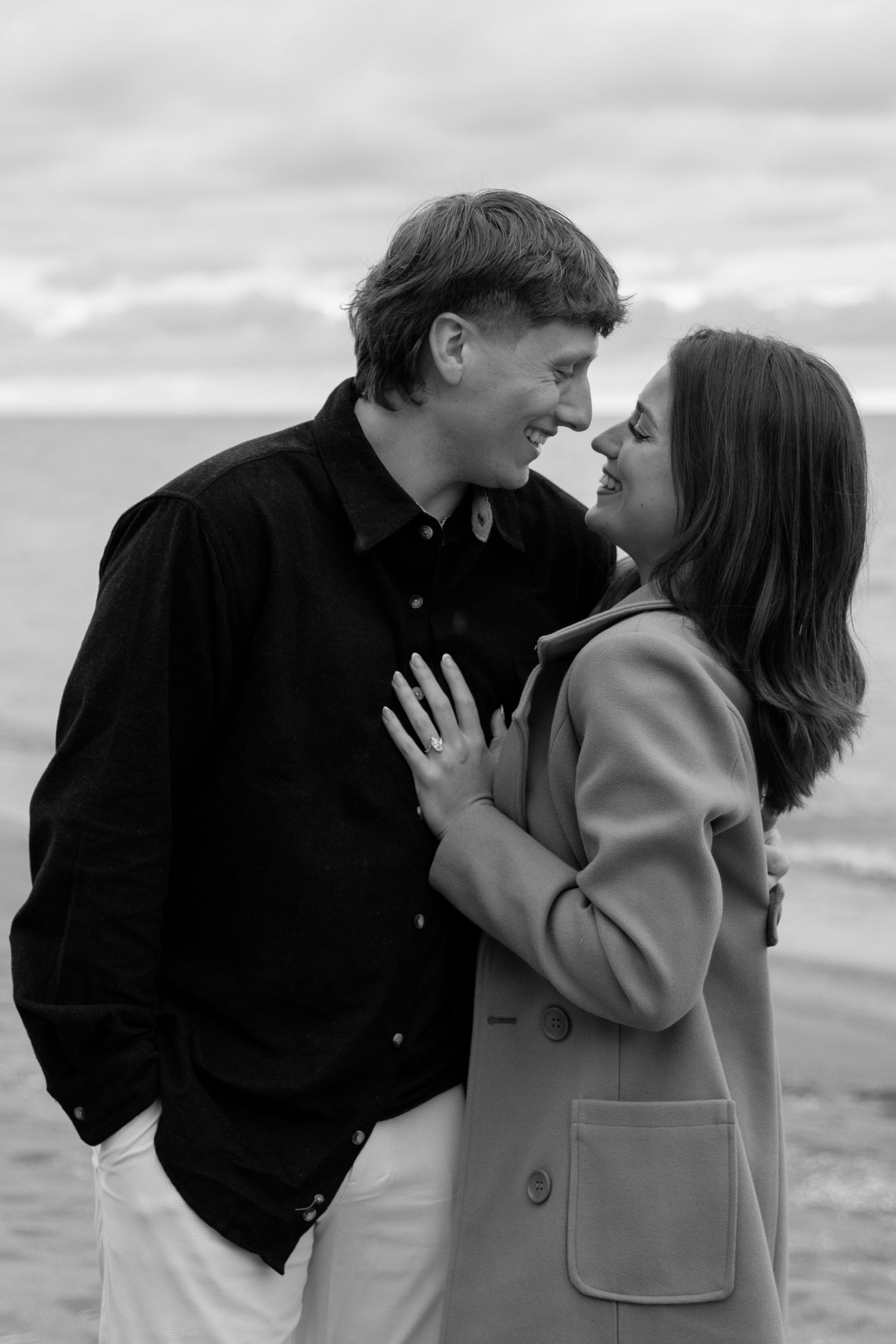 Black and white photo series captures intimate moments between a couple on a beach.