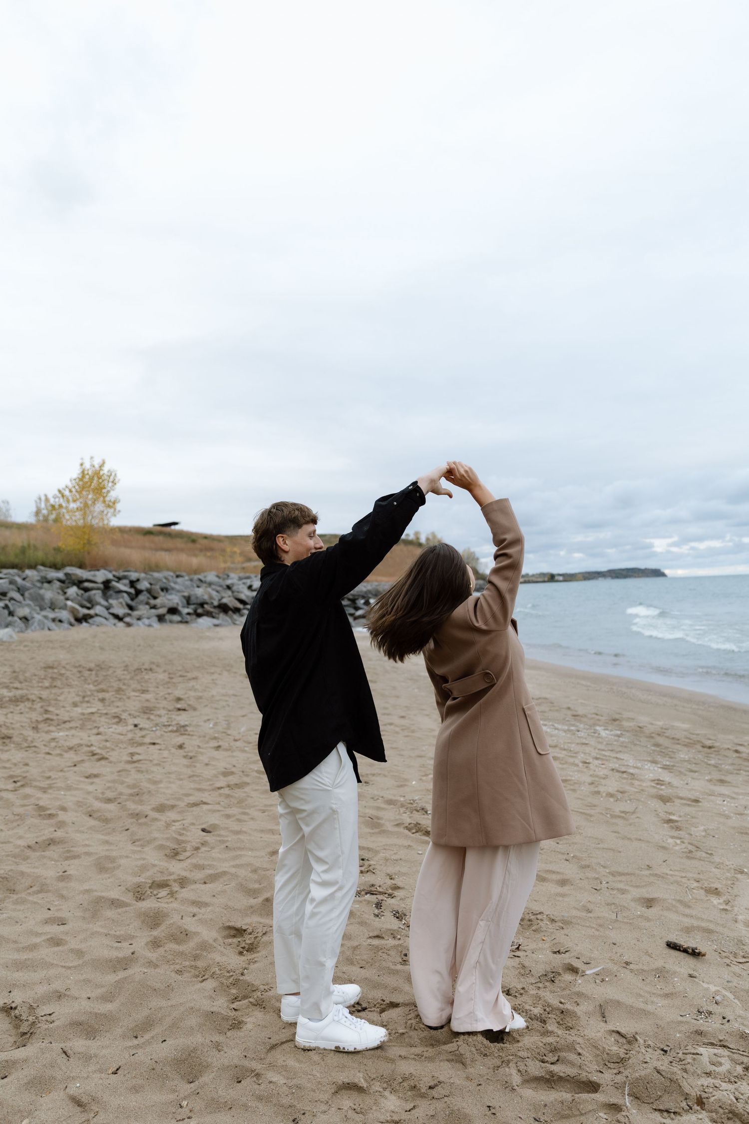 Two people in matching outfits strike playful poses on a sandy beach.