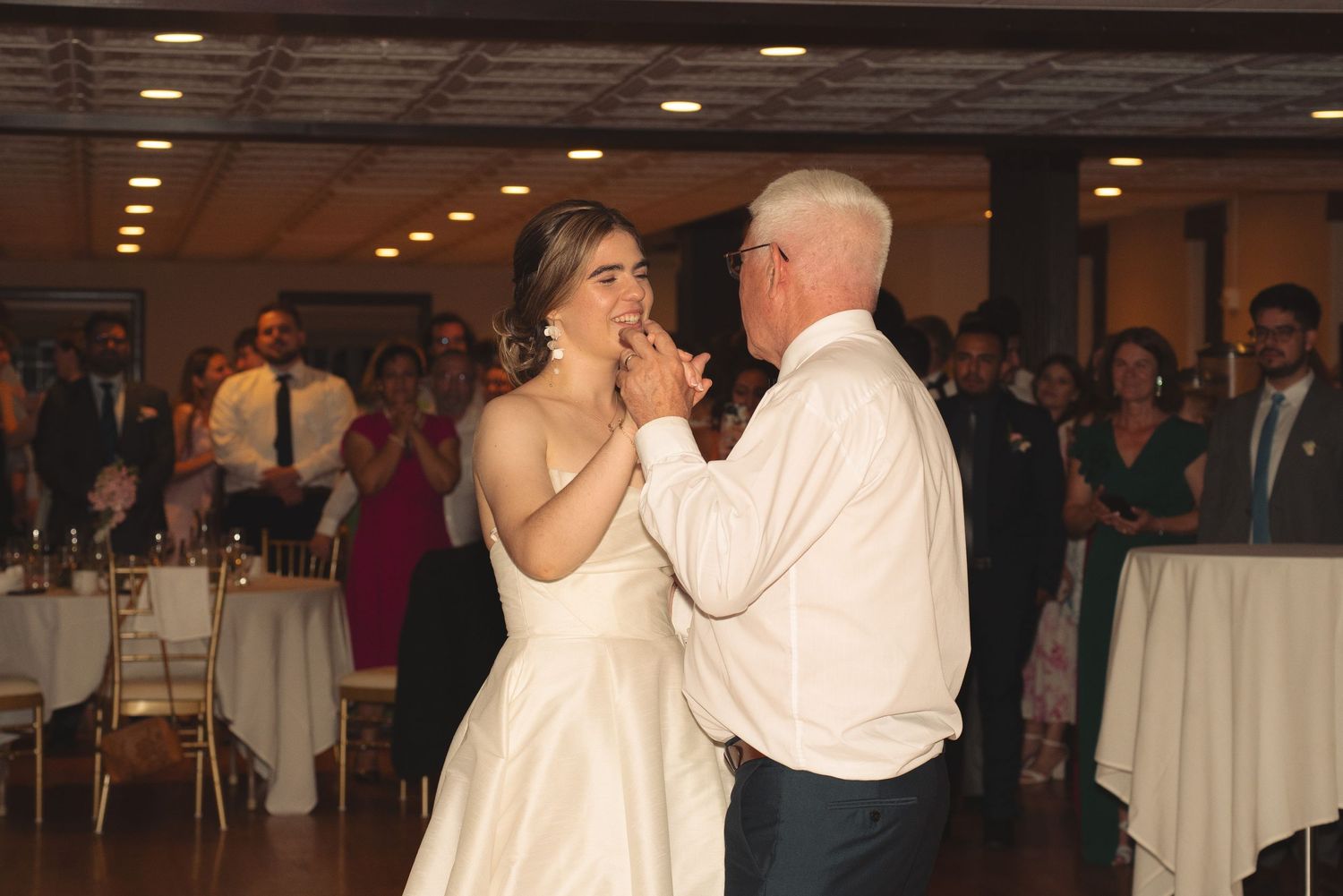 Couples dancing together at an indoor wedding reception with white tablecloths visible in the background.