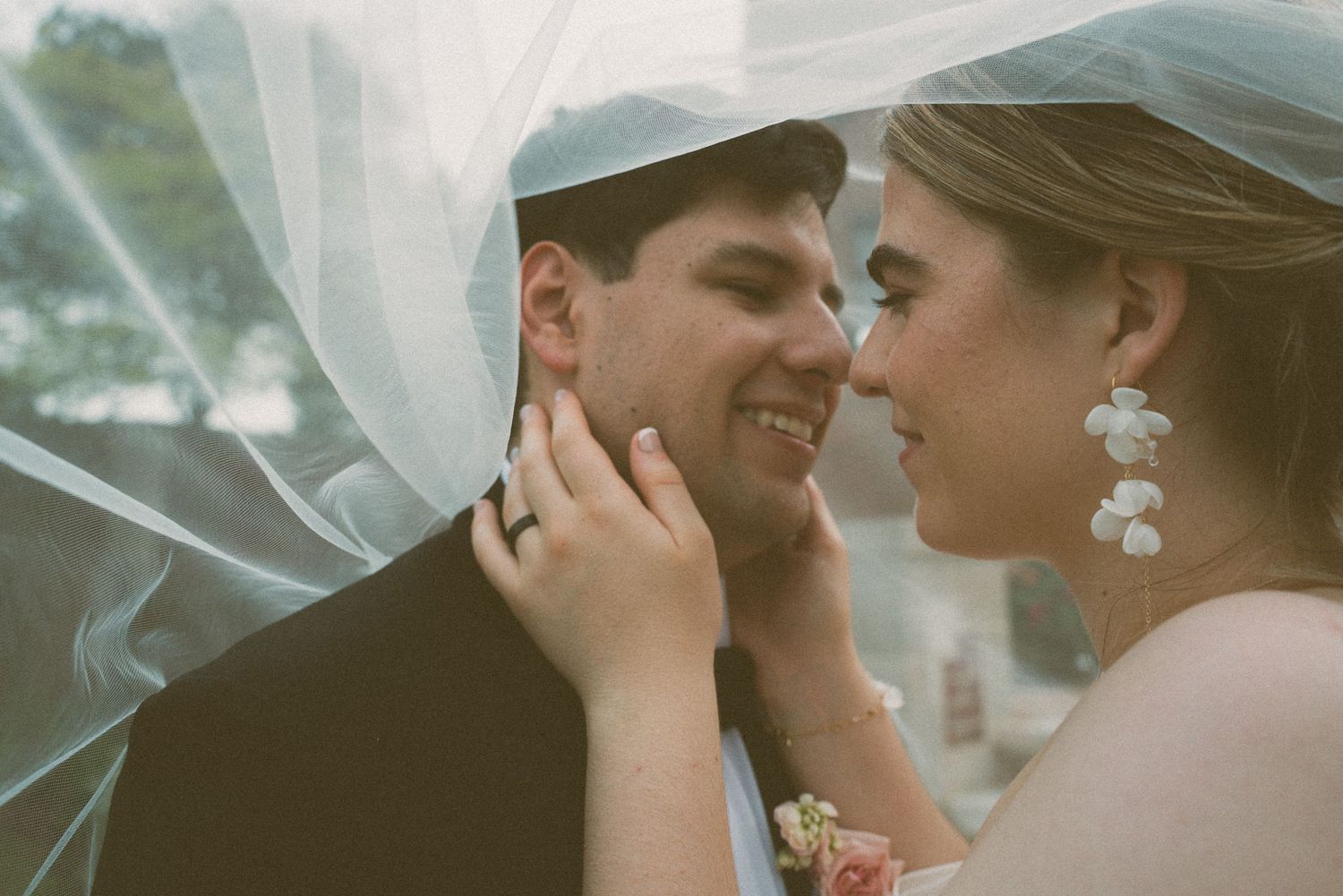 Romantic wedding portrait with couple sharing an intimate moment under flowing veil.