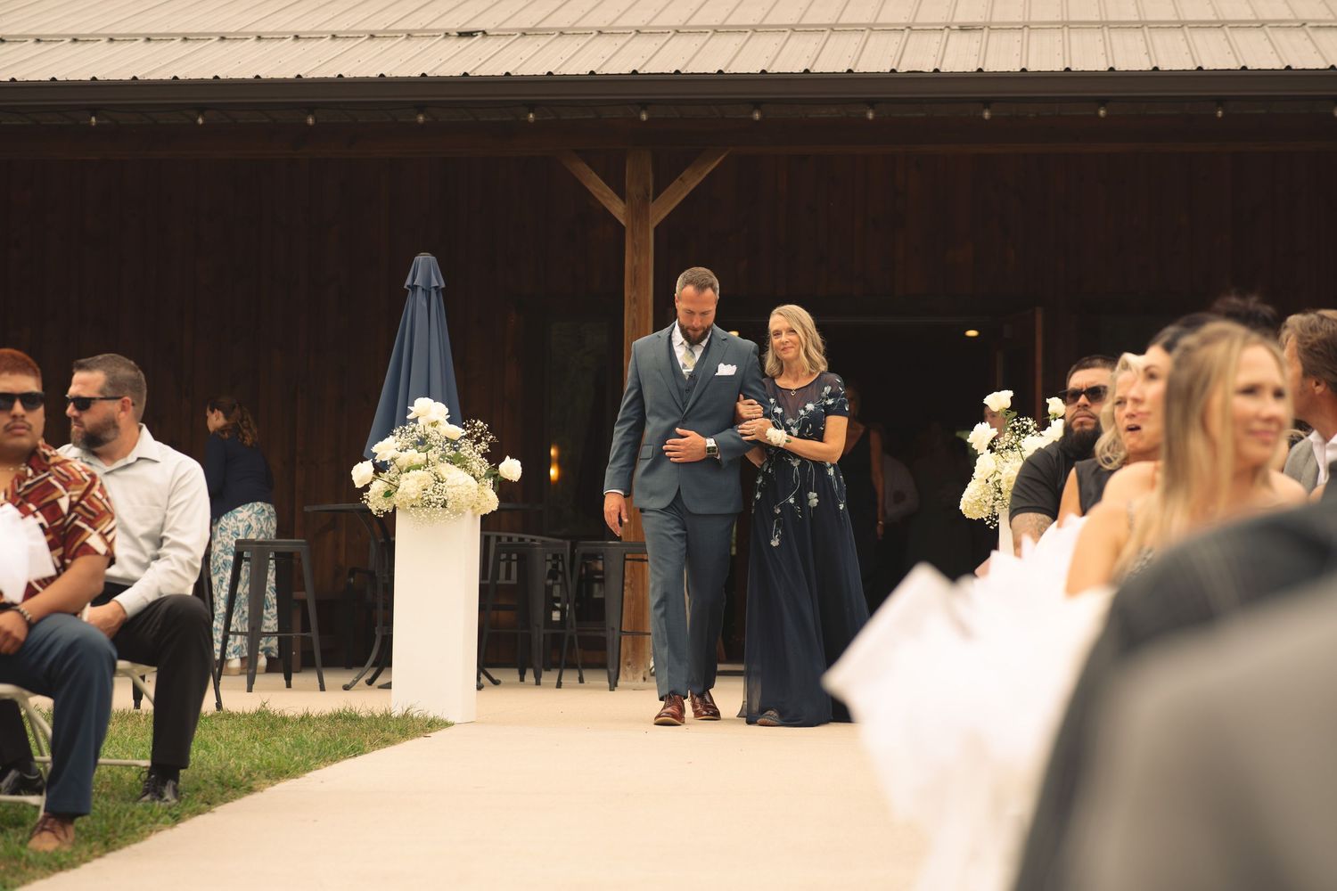 Wedding guests gather inside a rustic pavilion venue for ceremony.