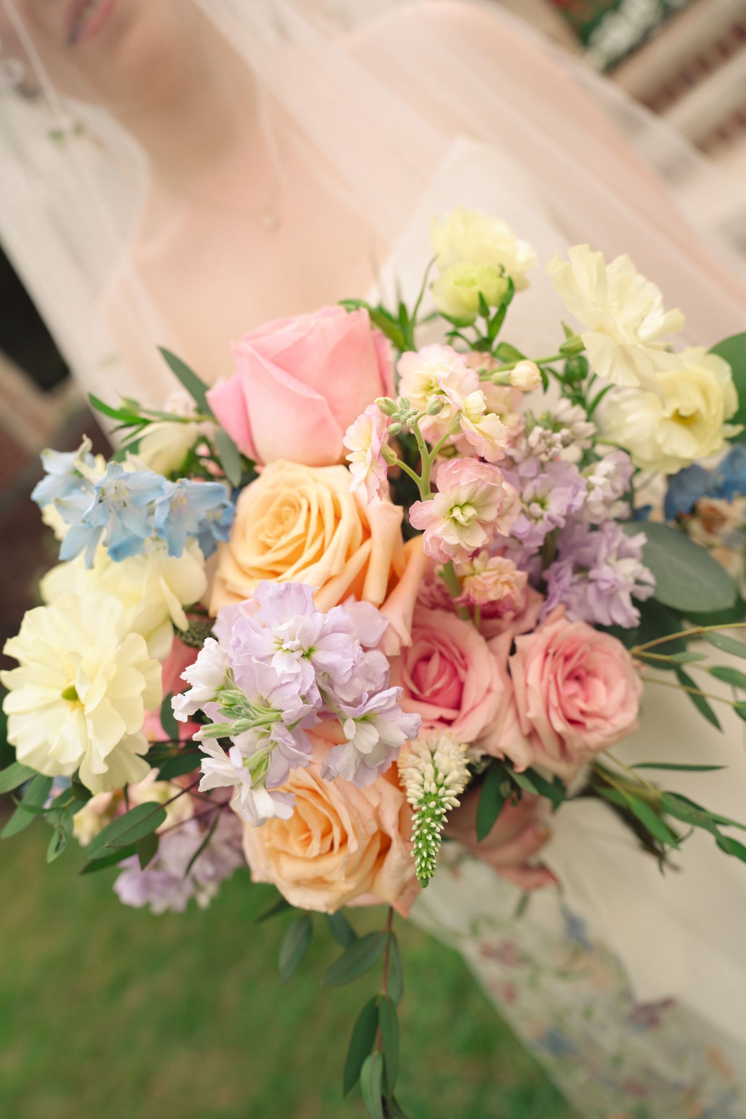Close-up of pastel wedding bouquet with roses, hydrangeas and delicate blue flowers.