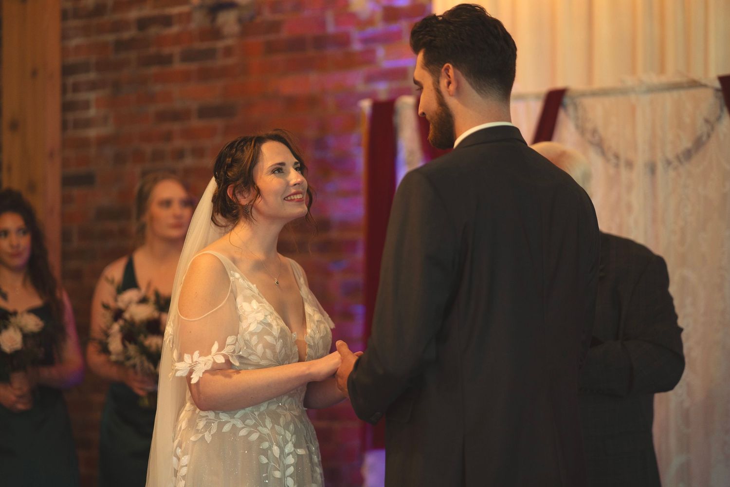 A romantic wedding dance scene in a rustic brick venue with string lights.