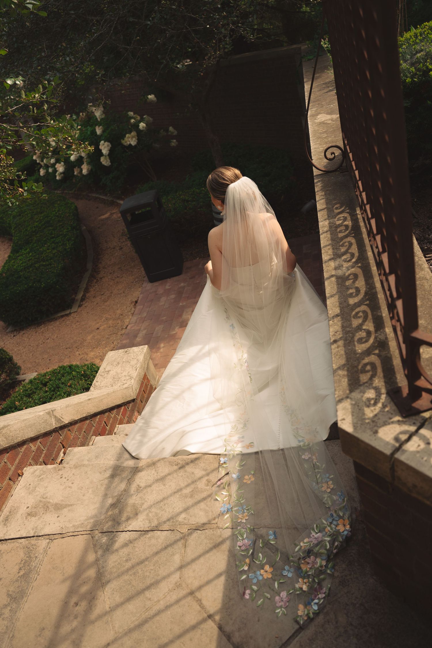 Wedding dress with embroidered details photographed outdoors in dappled sunlight.