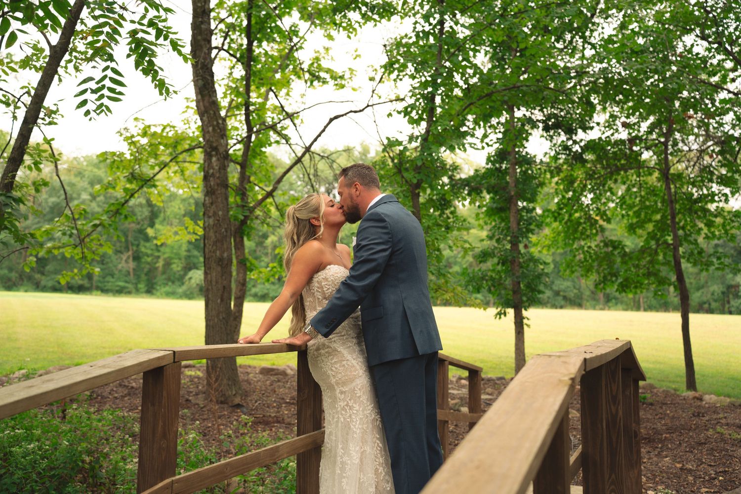 Romantic wedding photos captured on a wooden bridge pathway through the woods.