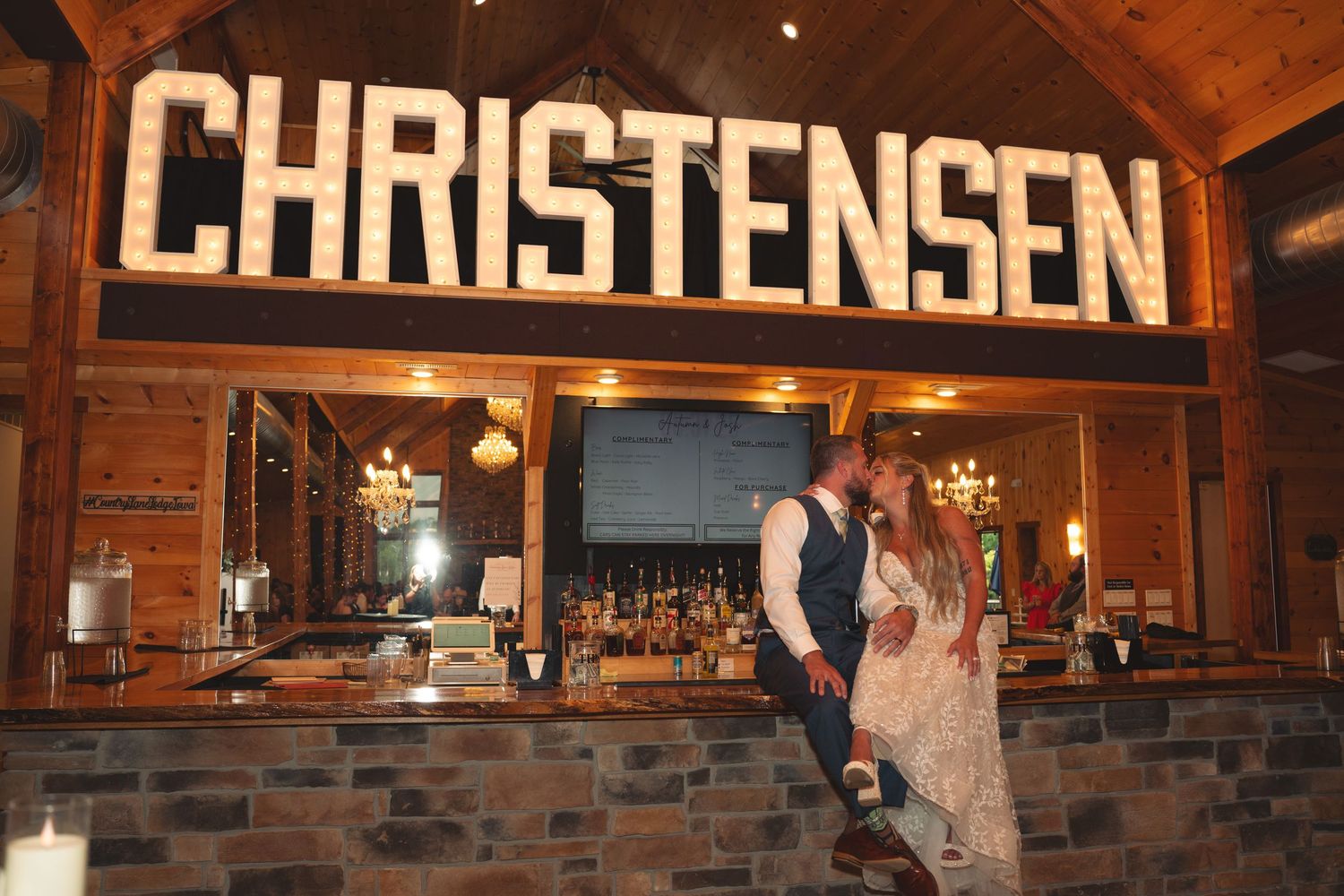 Rustic barn wedding venue with Christensen signage and exposed brick wall illuminated by warm lighting.