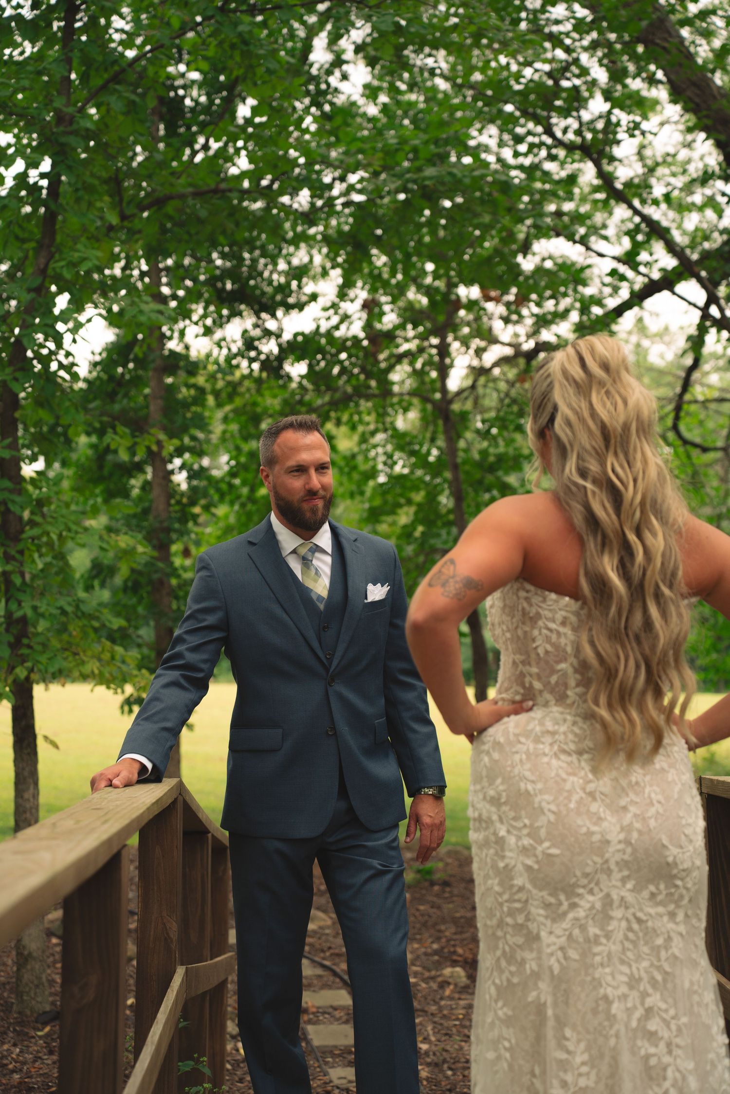Romantic first look moment between newlyweds on a wooden deck surrounded by trees.