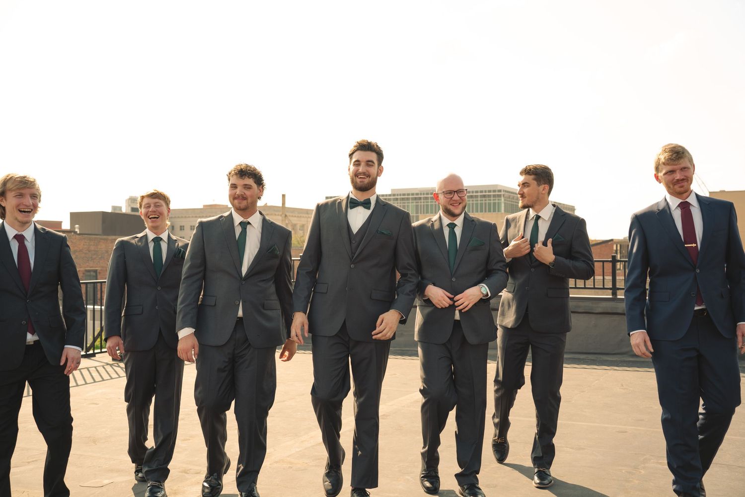 Wedding party in formal attire walking together across an outdoor venue.