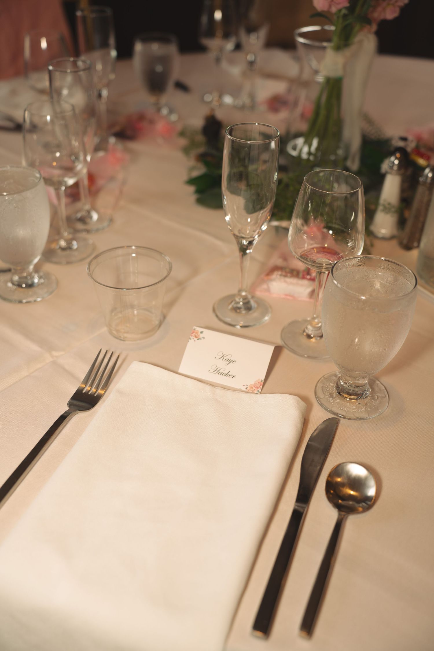 Place setting with white napkin, silverware and multiple glasses on an elegant dining table.