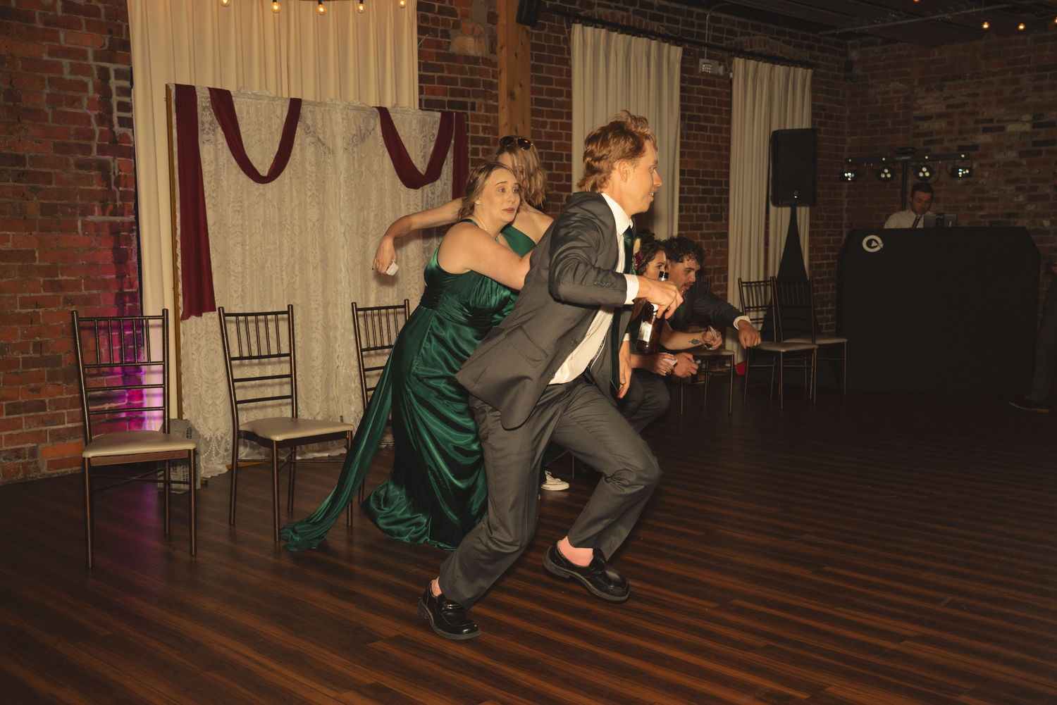 Wedding reception dance floor with guests enjoying lively dancing in rustic brick venue.