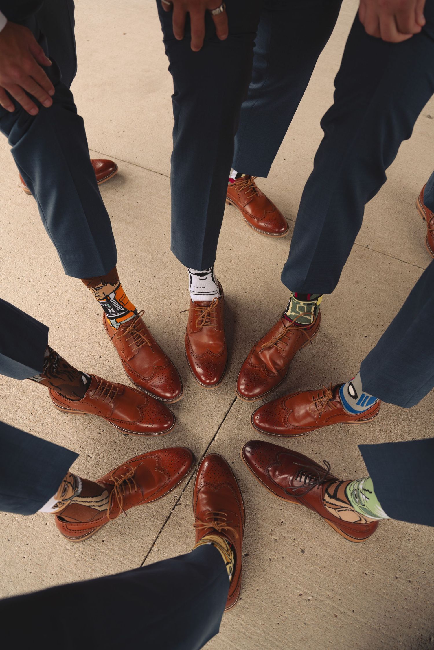 Group photo of brown leather dress shoes worn by wedding party members standing in circle.