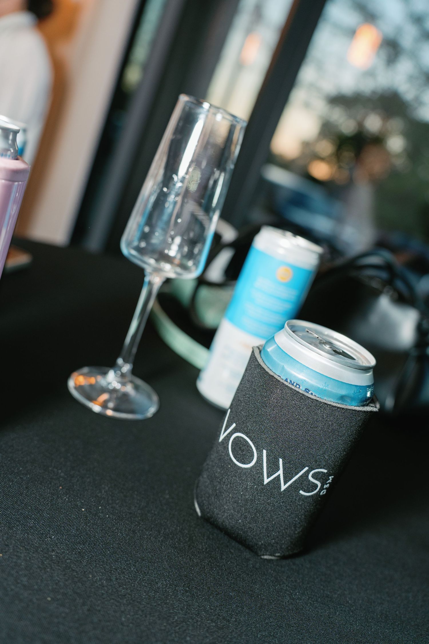 Wedding reception table with champagne flute and can in a black VOWS koozie.