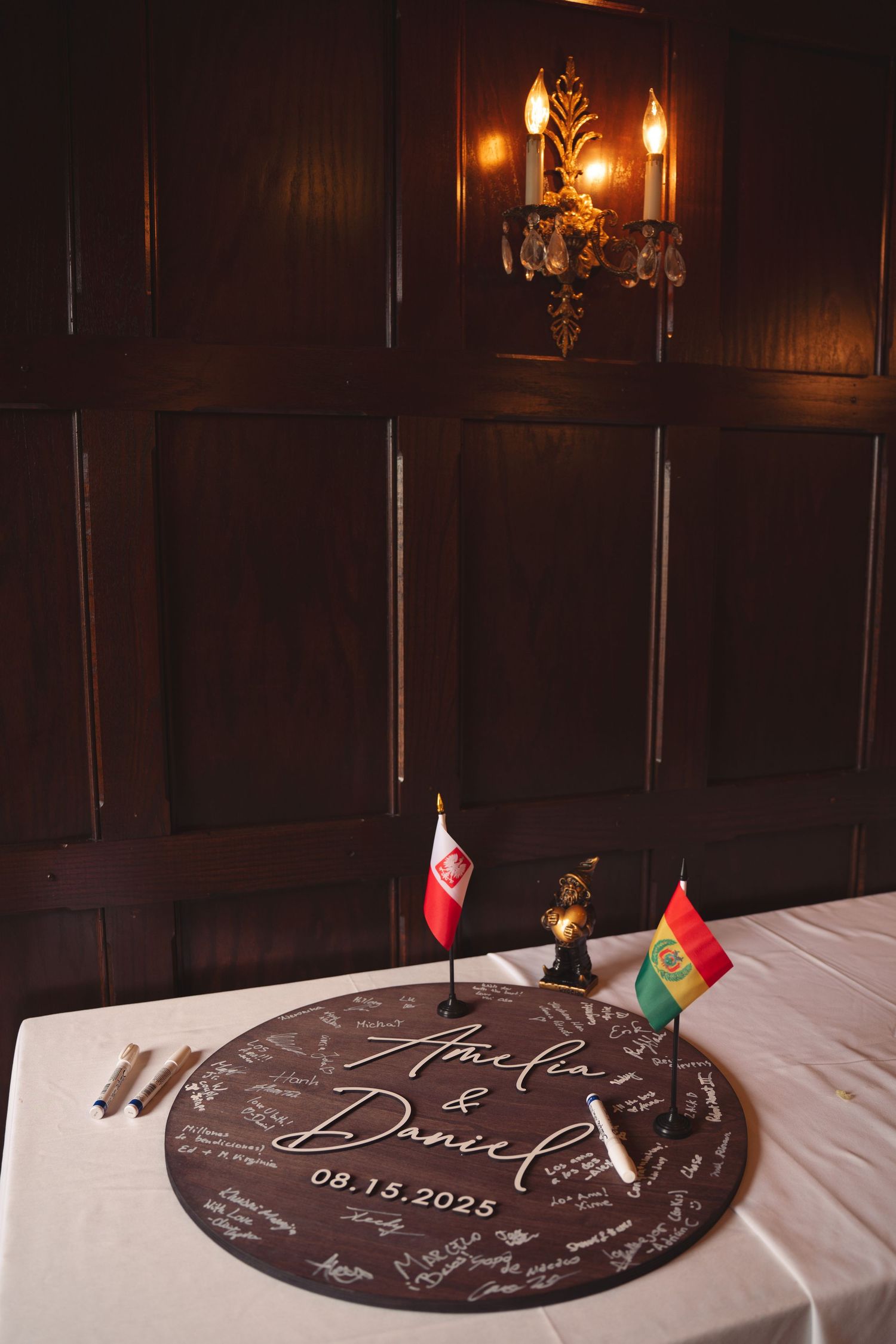 Wedding reception table with dark wooden guestbook and decorative flags.