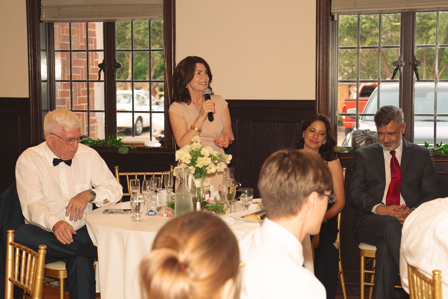 Wedding reception hall filled with guests dining at decorated tables.