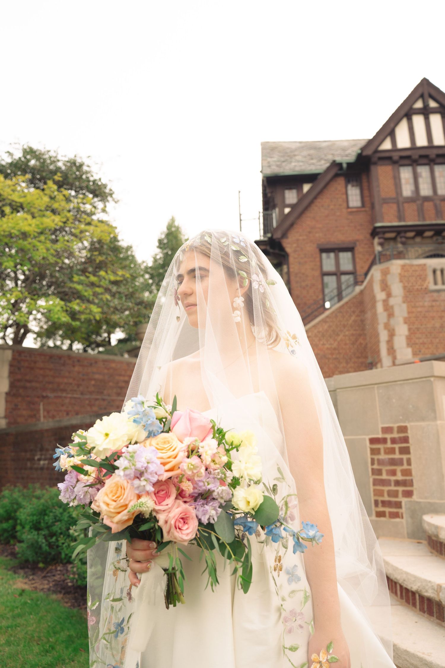 Bridal veil adorned with delicate floral crown against Tudor mansion backdrop.