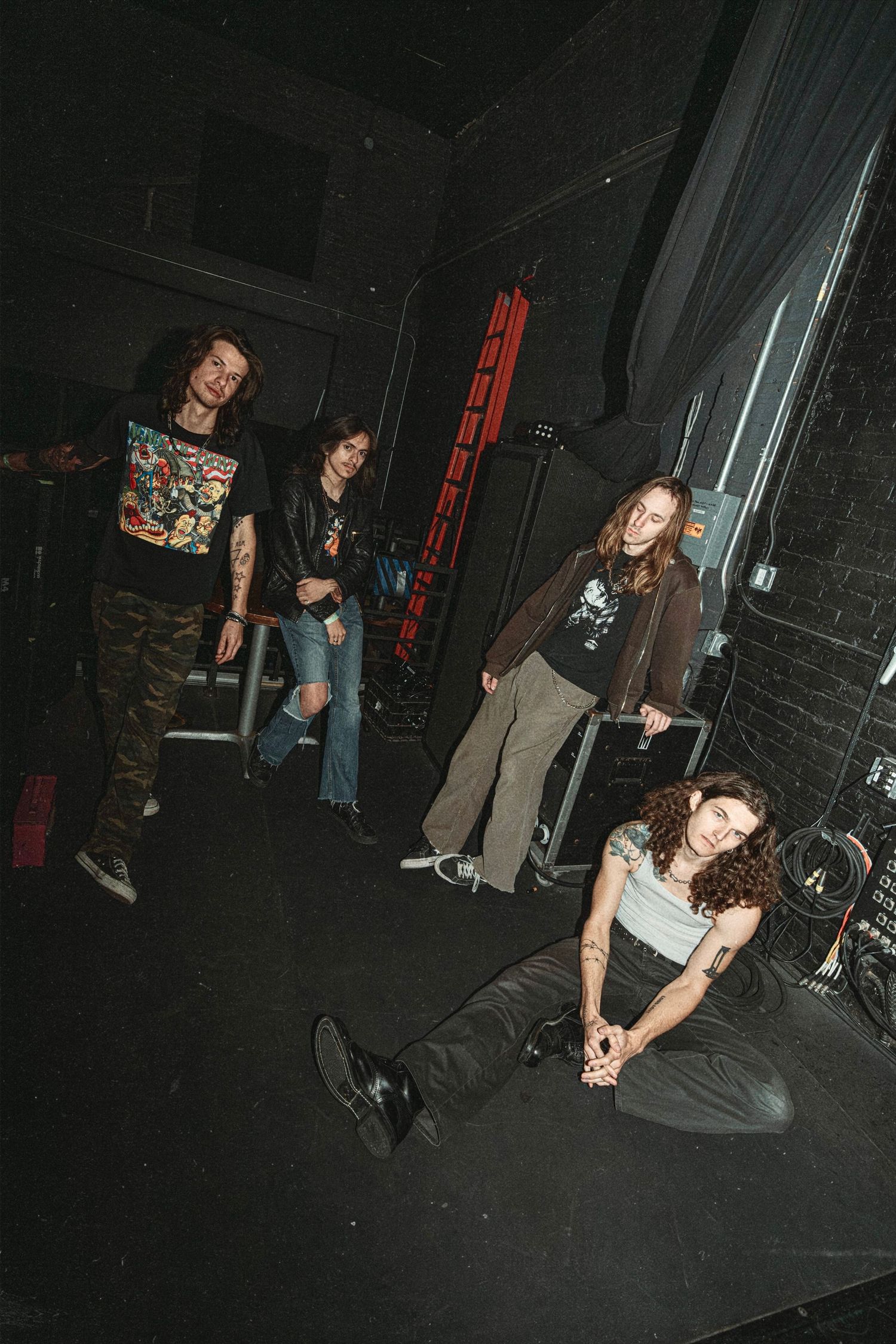 Dark indoor scene with multiple people sitting on a black floor.