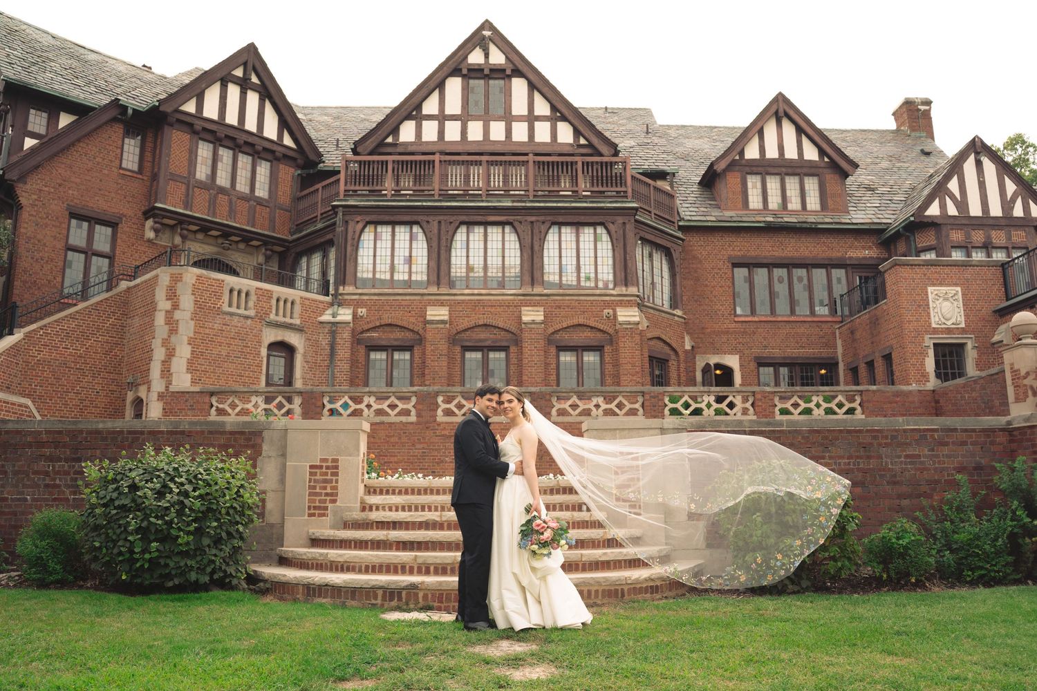 Panoramic view of a Tudor-style mansion with brick facade and ornate architectural details.