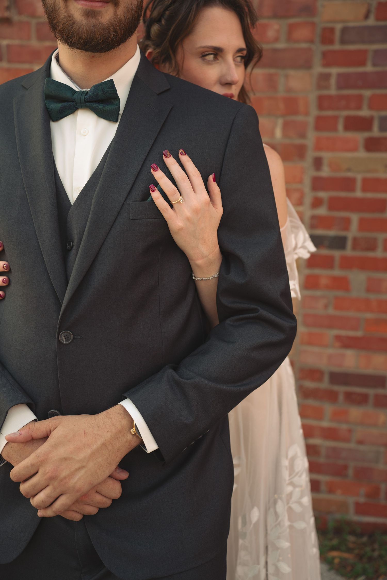 Close-up details of formal wedding attire against a brick wall background.