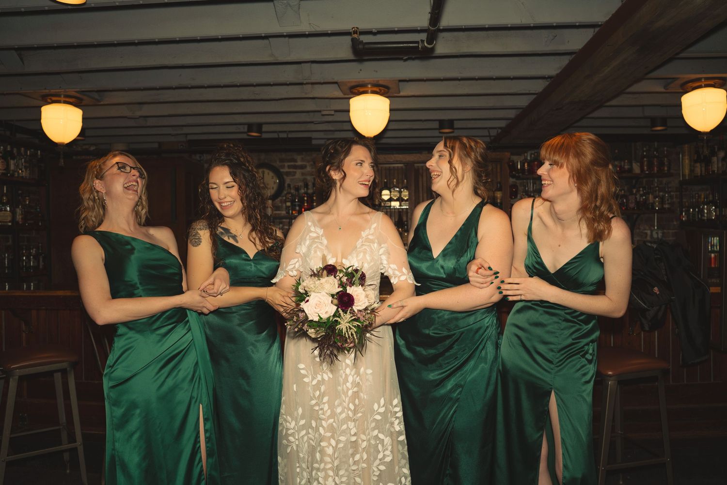 Wedding party dancing and celebrating in rustic indoor venue with string lights.