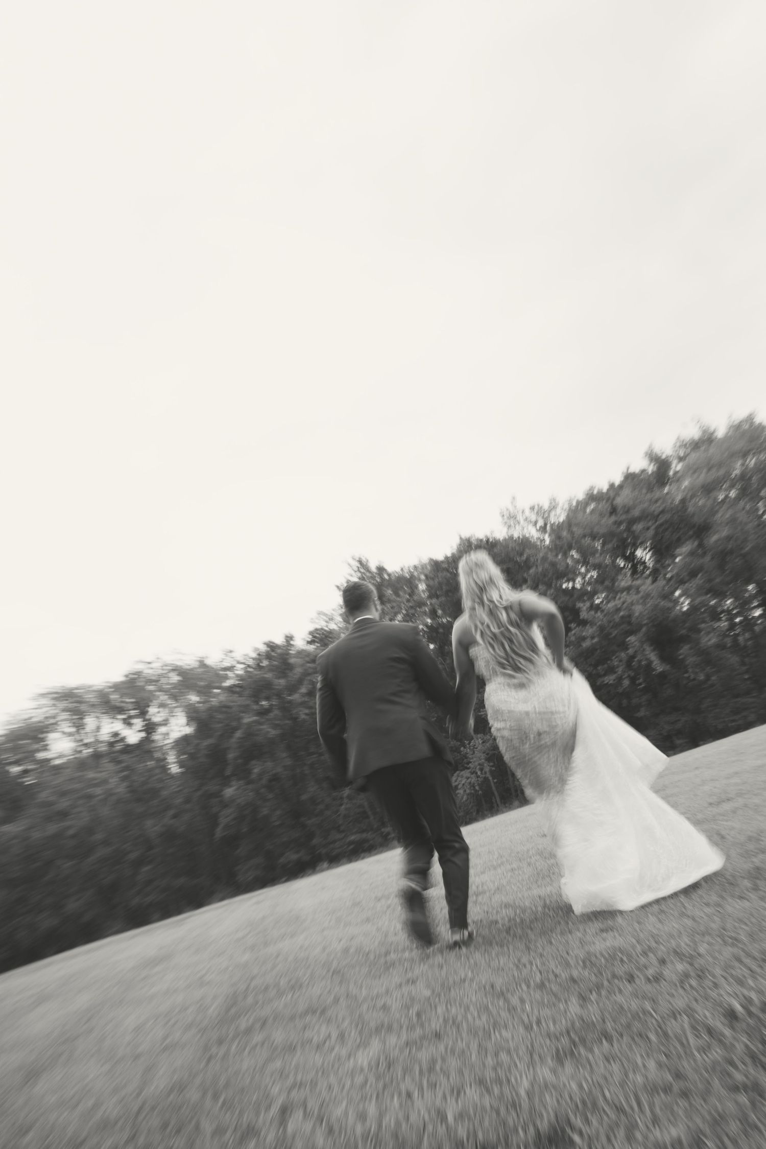 Dynamic black and white shots of newlyweds moving through an open field.