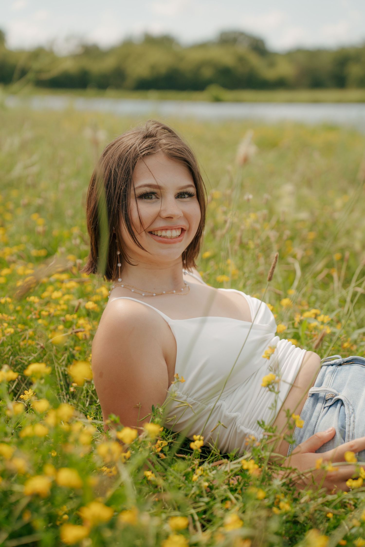 Person in white dress lying in field of yellow wildflowers on sunny day.