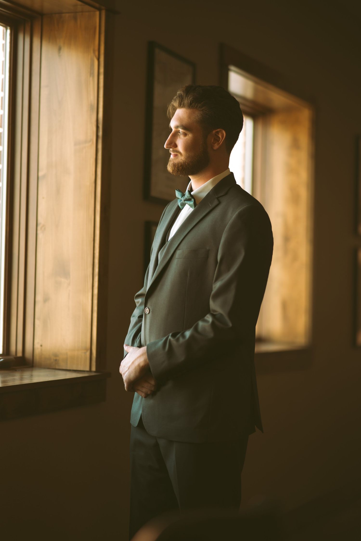 Atmospheric portrait in dark room with natural window lighting.