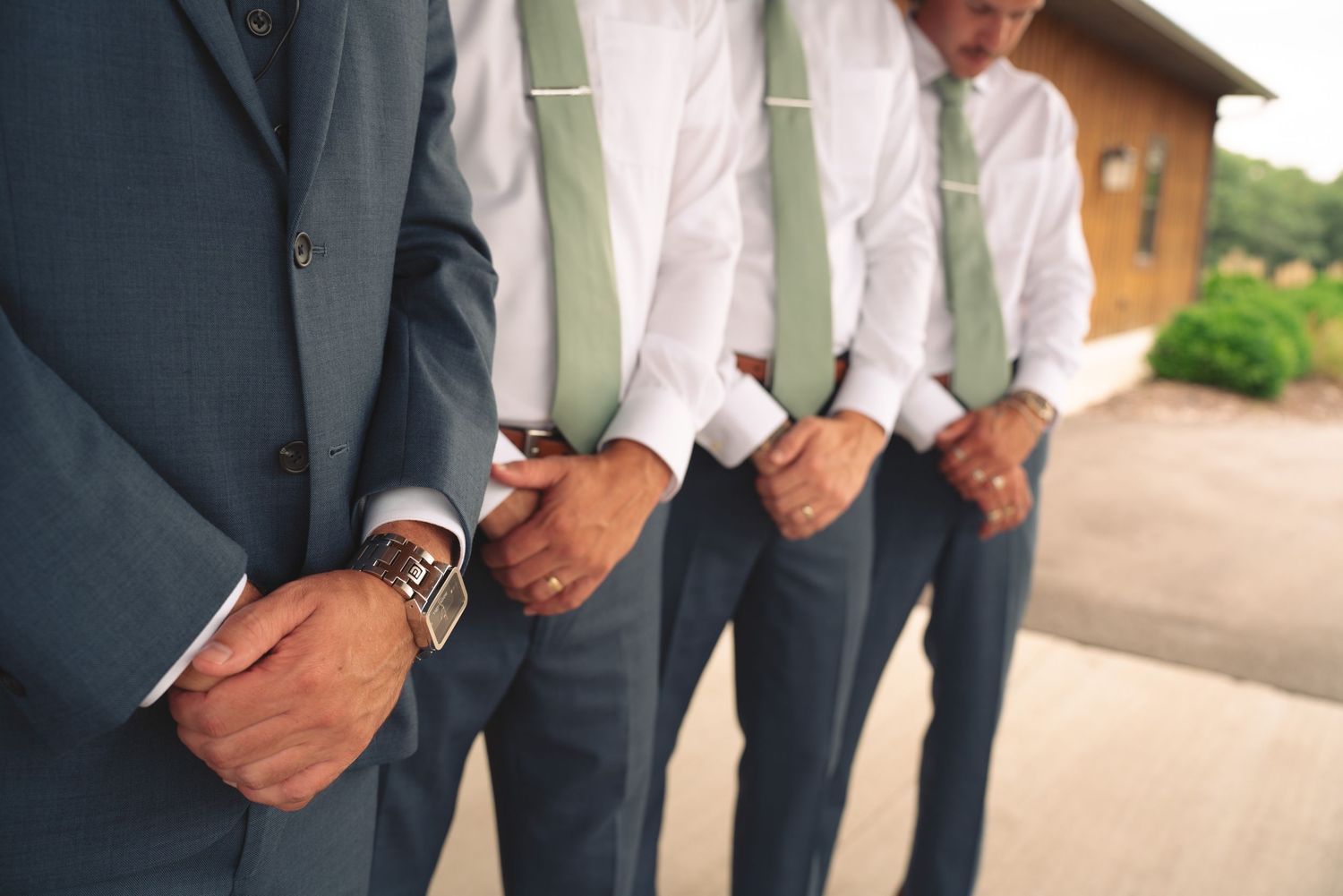 Wedding party members in navy suits pose together against a rustic wooden backdrop.
