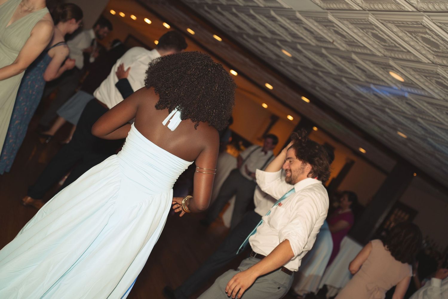 Couples dancing at a wedding reception with ambient lighting and wooden floors.