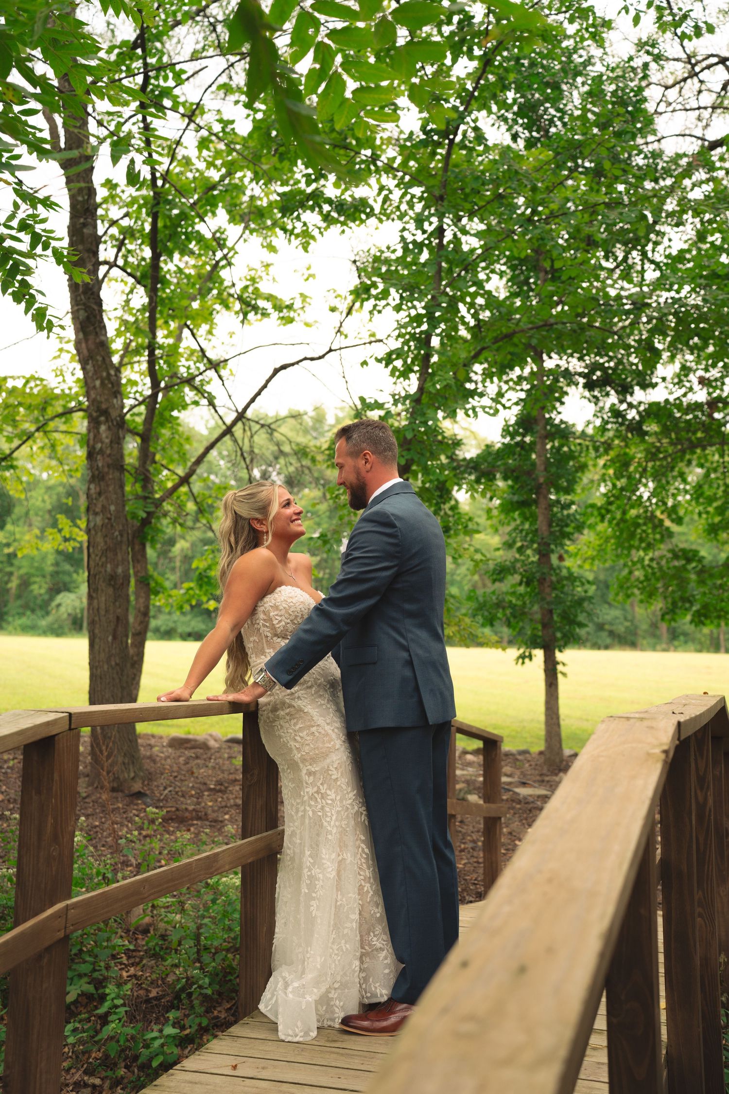 Couple sharing intimate moments on a wooden bridge in a natural outdoor setting.