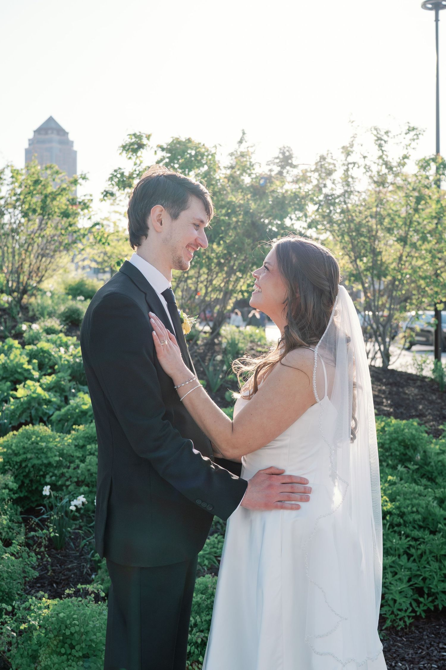 Bride and groom share a romantic moment in a lush garden, with the bride in a white gown and veil.