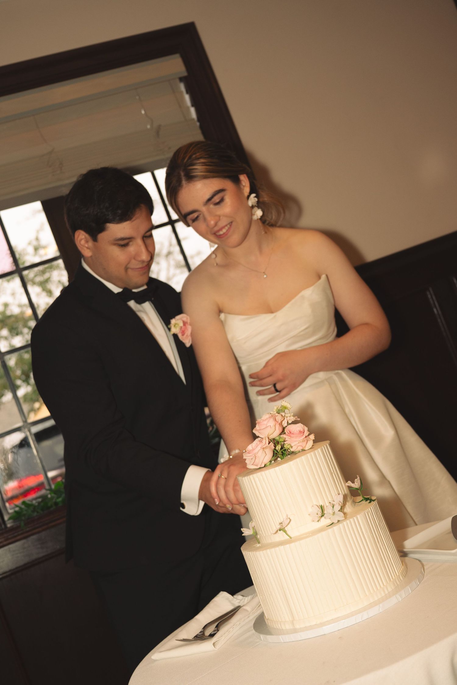 Couple sharing a moment while cutting their elegant white wedding cake.