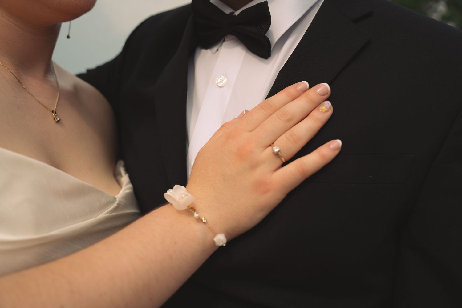 Close-up detail of formal wedding attire showing bow tie and hands.