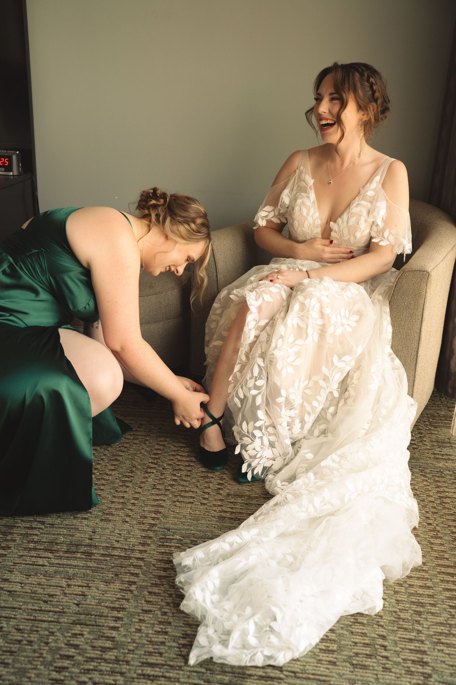 Elegant lace wedding dress details shown while someone sits in an upholstered chair.