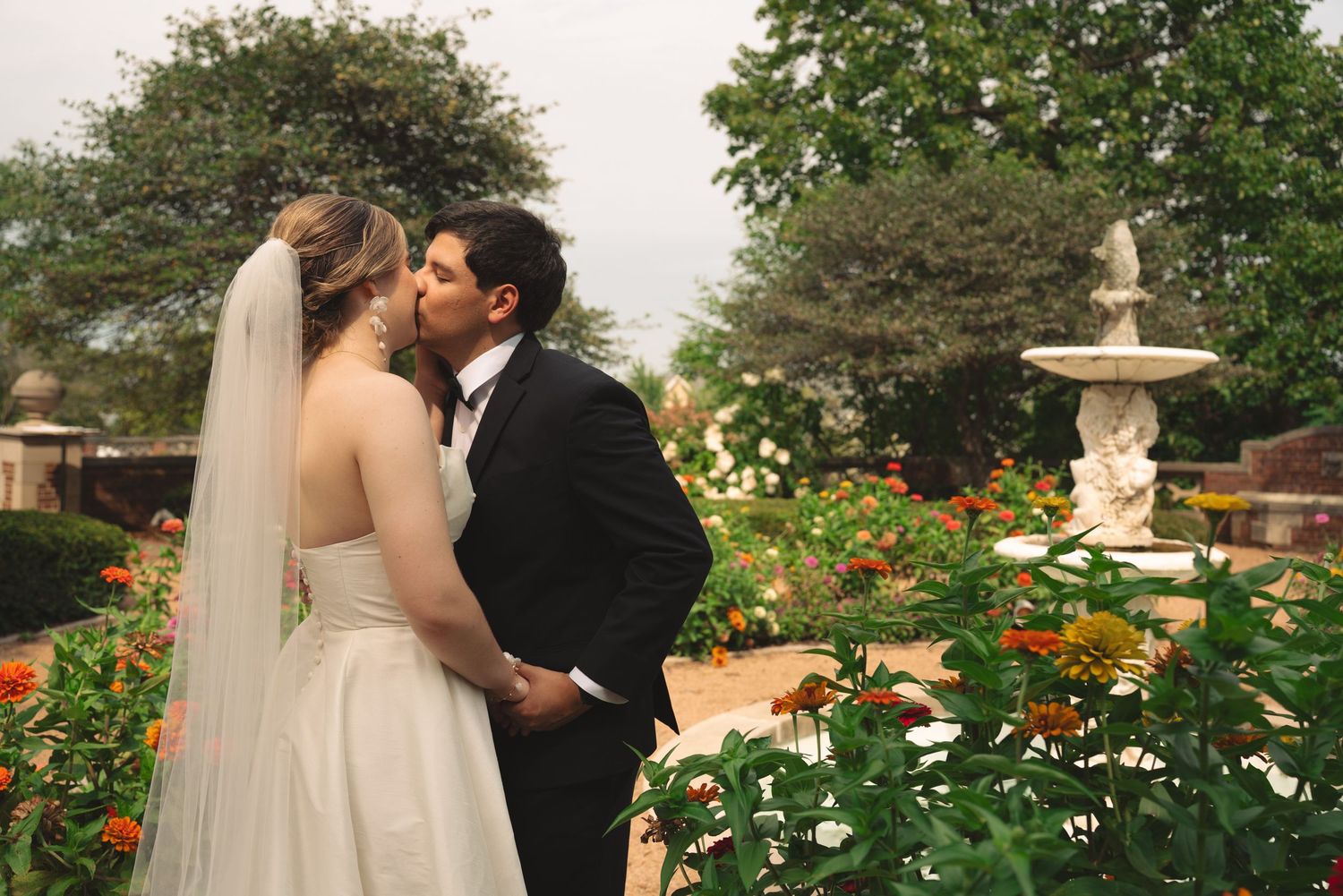 Romantic wedding moment captured in a lush garden setting with flowering plants.