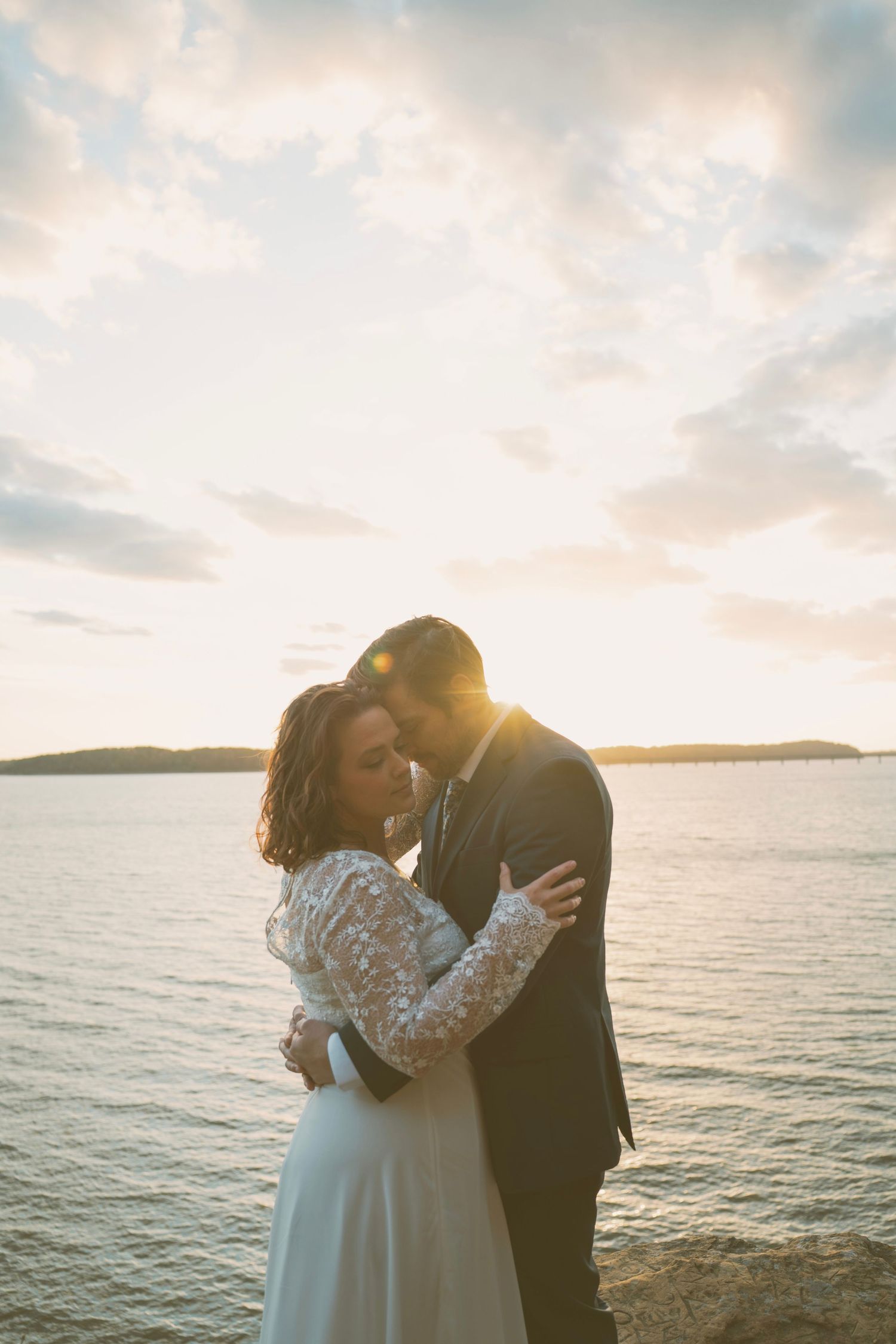 Romantic sunset beach wedding photoshoot with couple embracing by the ocean.