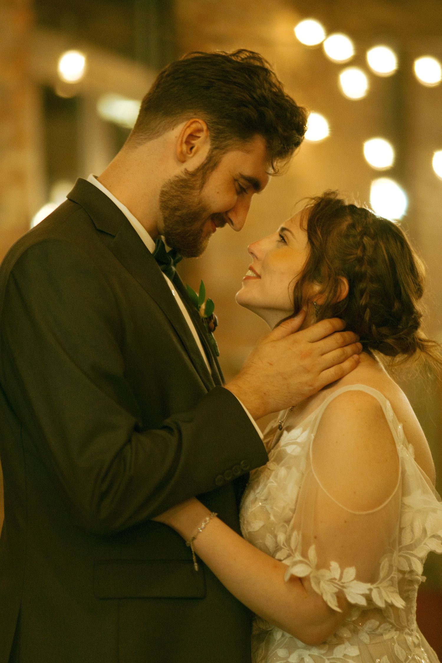 Romantic wedding moment captured in warm lighting against industrial brick backdrop.