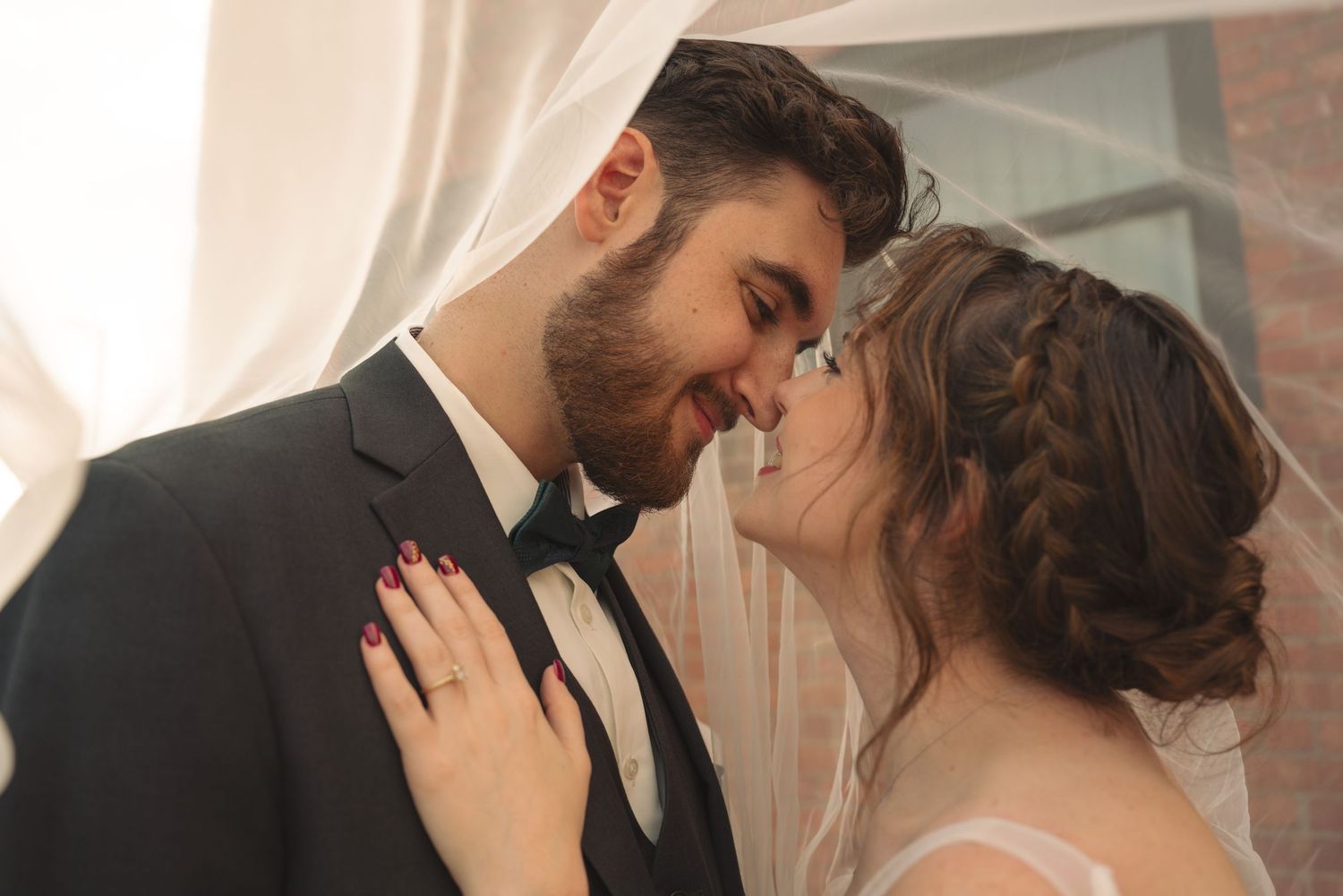 A romantic wedding moment captured in soft light as newlyweds share an intimate kiss.