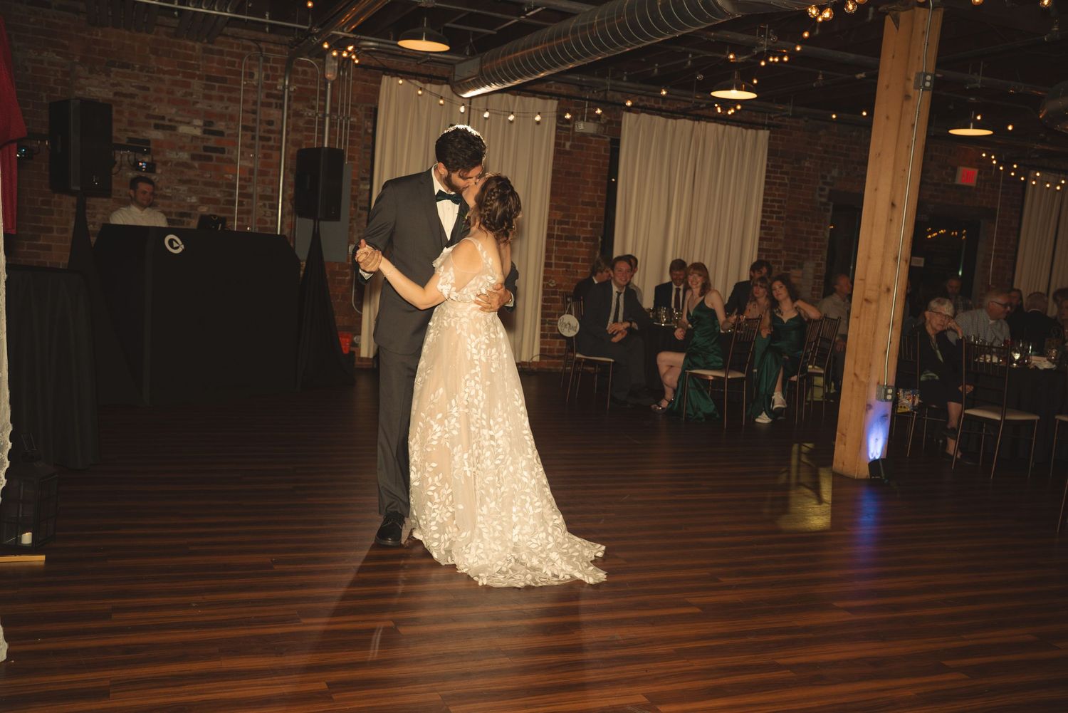 Wedding celebration in a rustic venue with exposed brick walls and hardwood floors.