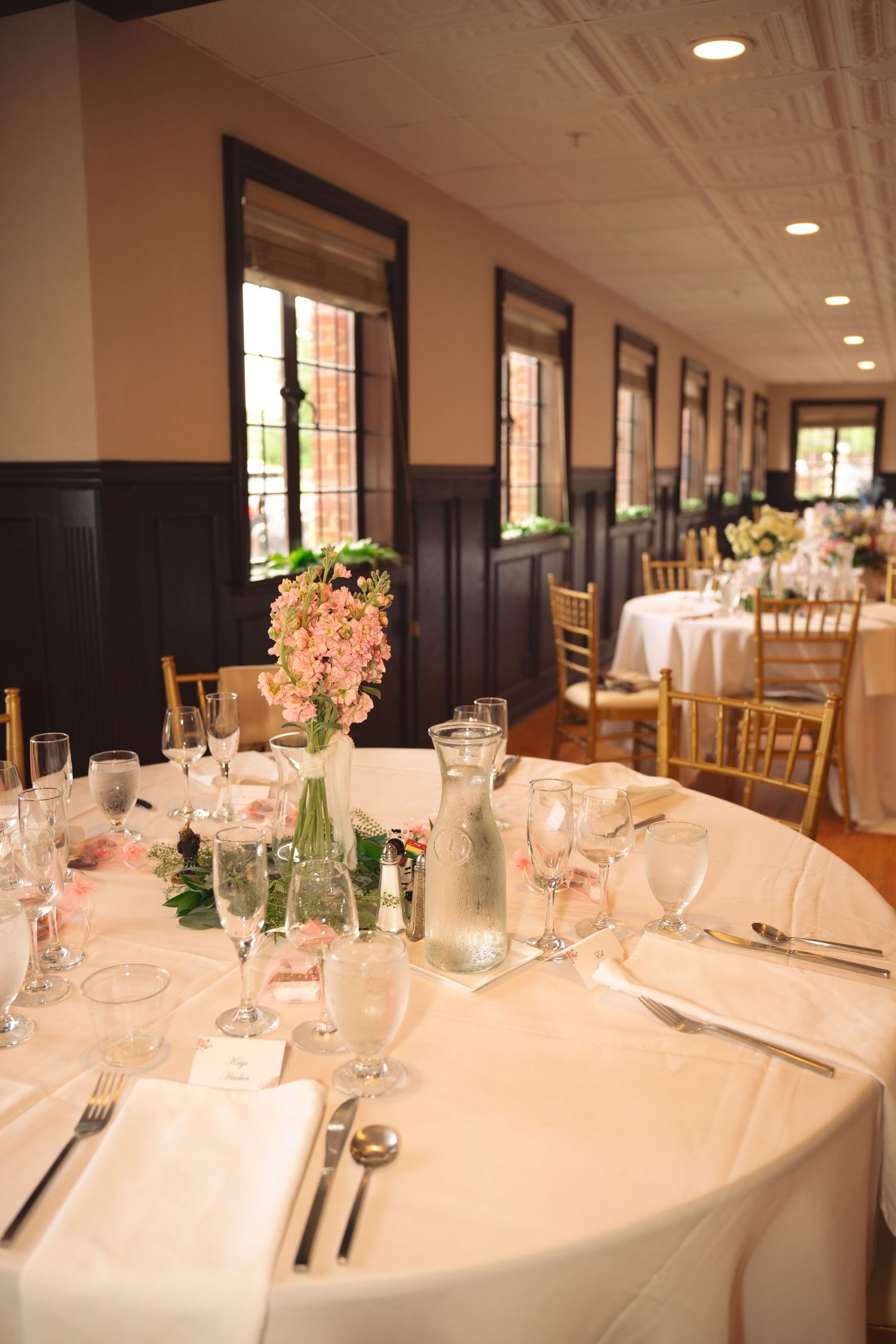Long banquet tables with elegant place settings and pink floral centerpieces.