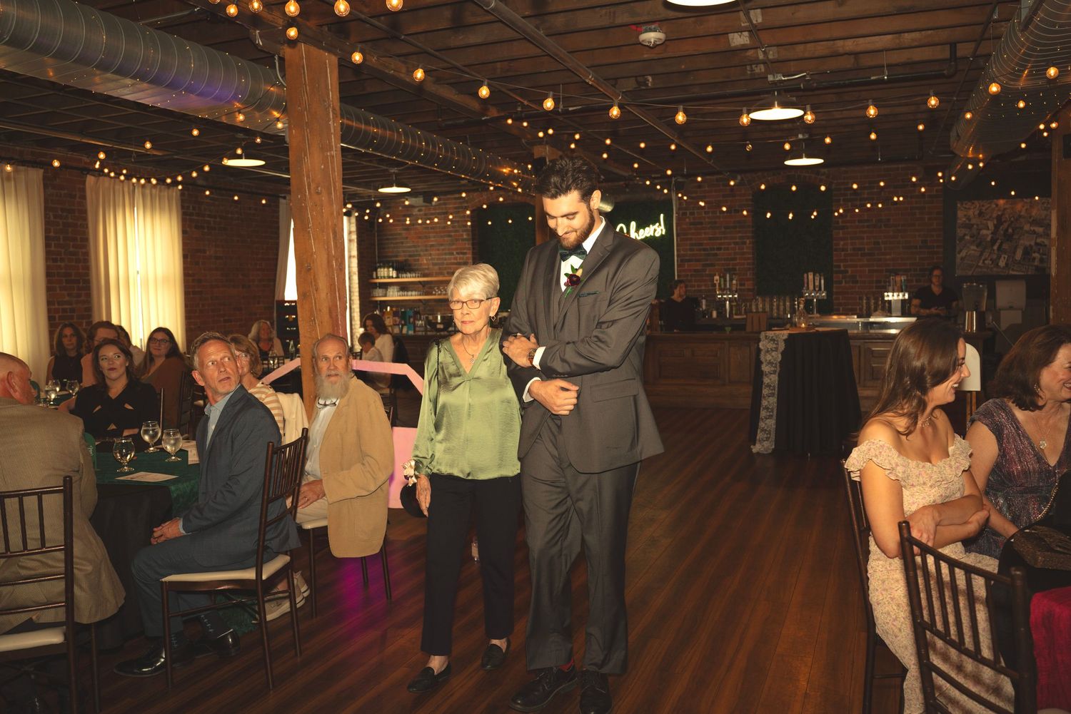 Wedding reception dance floor filled with guests under warm lighting.